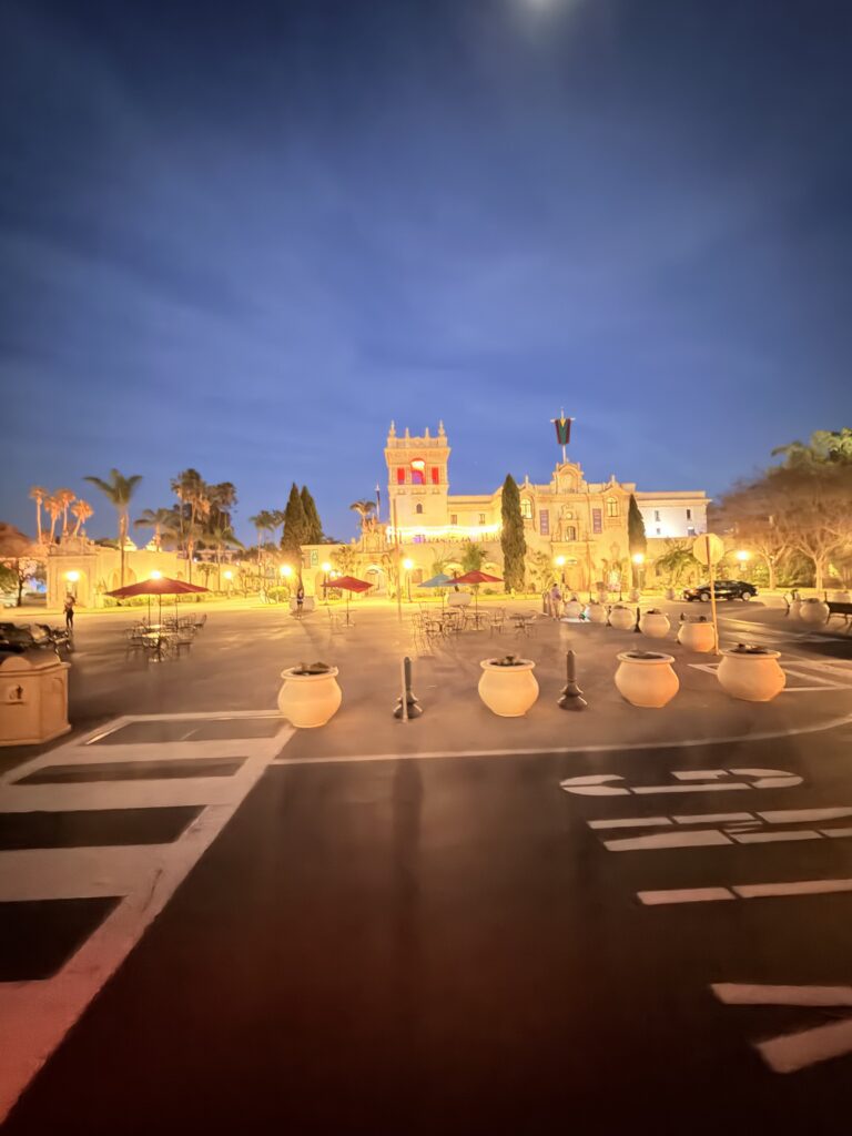 Beleuchtetes historisches Gebäude im spanischen Kolonialstil im Balboa Park San Diego bei Nacht mit Türmchen, Palmen und Platz im Vordergrund